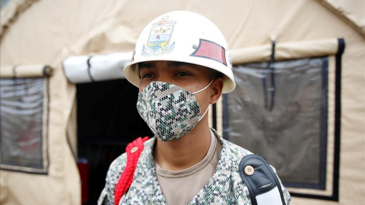 Un soldado colombiano con una mascarilla monta guardia en un estacionamiento donde se han levantado tiendas medicalizadas junto a un hospital militar en Bogotá. Un soldado colombiano con una mascarilla monta guardia en un estacionamiento donde se han levantado tiendas medicalizadas junto a un hospital militar en Bogotá.