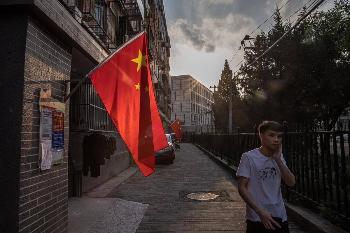 Un hombre camina junto a un edificio residencial decorado con banderas nacionales, en los días previos a la celebración del Día Nacional de China, en Pekín, el 28 de septiembre. 