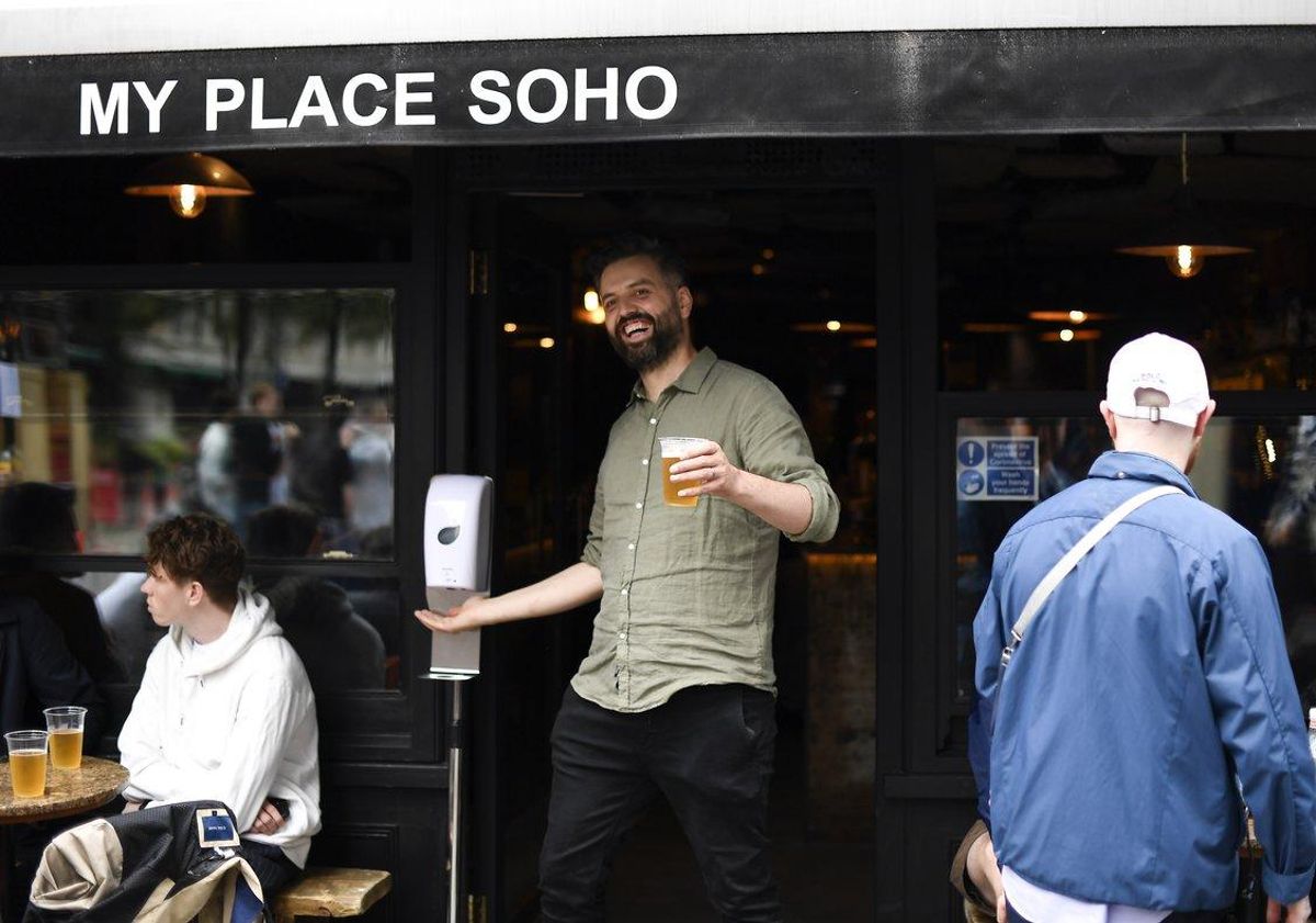 Un hombre sale con una cerveza en la mano de un pub en Londres. Un hombre sale con una cerveza en la mano de un pub en Londres.