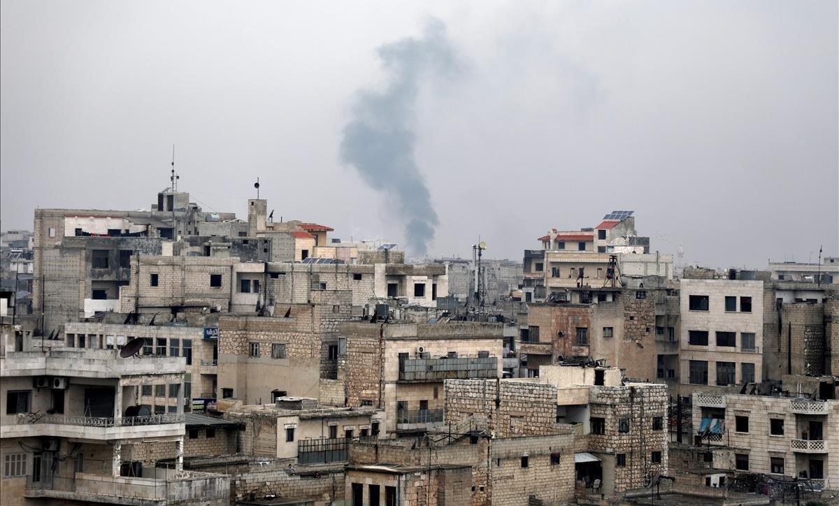 Una columna de humo se eleva sobre los escombros durante un bombardeo de las fuerzas gubernamentales sirias en Sarman, en Idlib.