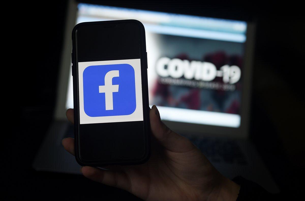 El logo de Facebook en un móvil frente a una pantalla sobre el covid-19.