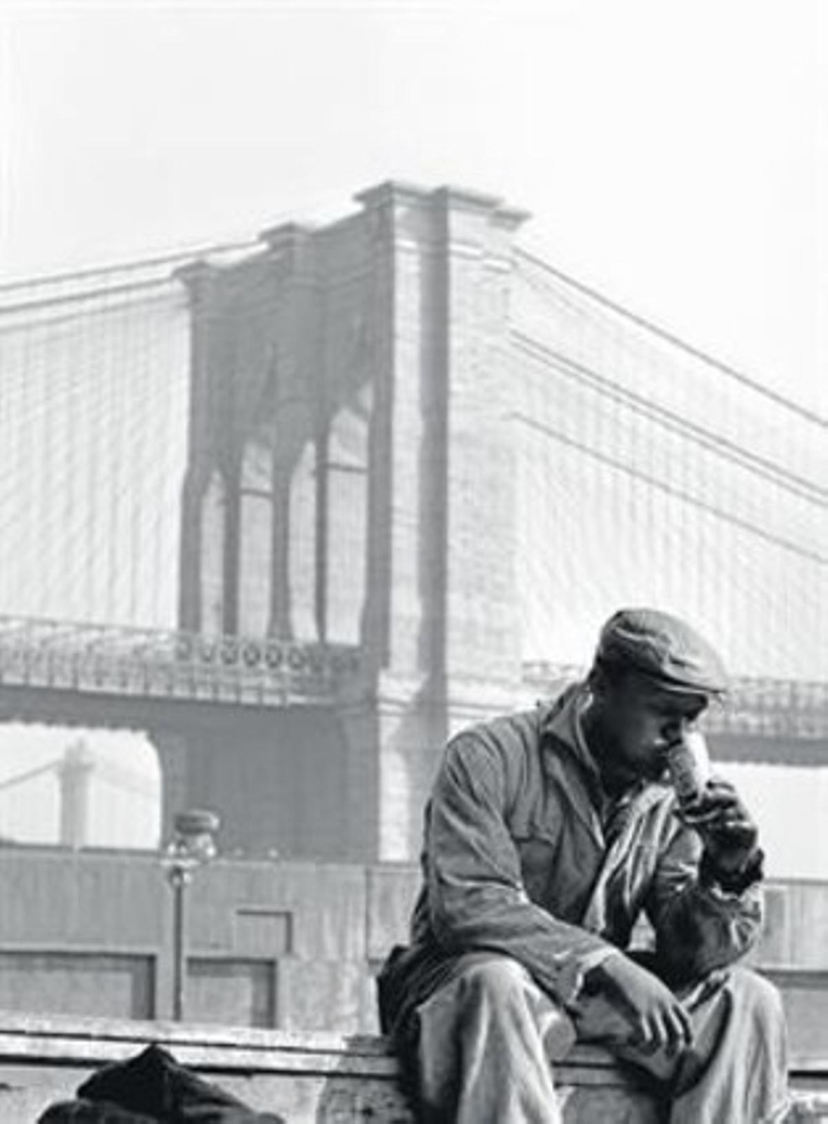 Un trabajador se toma un respiro ante el puente de Brooklyn, en 1955.