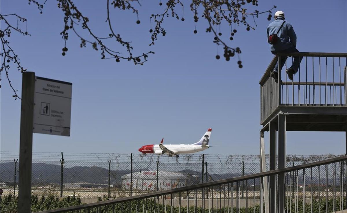 Un hombre observa el aterrizaje de un avión en el aeropuerto desde uno de los miradores del delta del Llobregat.