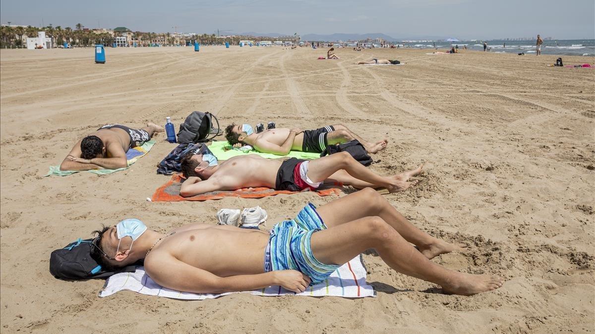 Bañistas con mascarilla, en la playa de la Malvarrosa, en València.