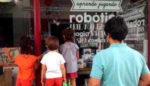 Un padre mira con sus hijos el escaparate de una tienda infantil de robótica