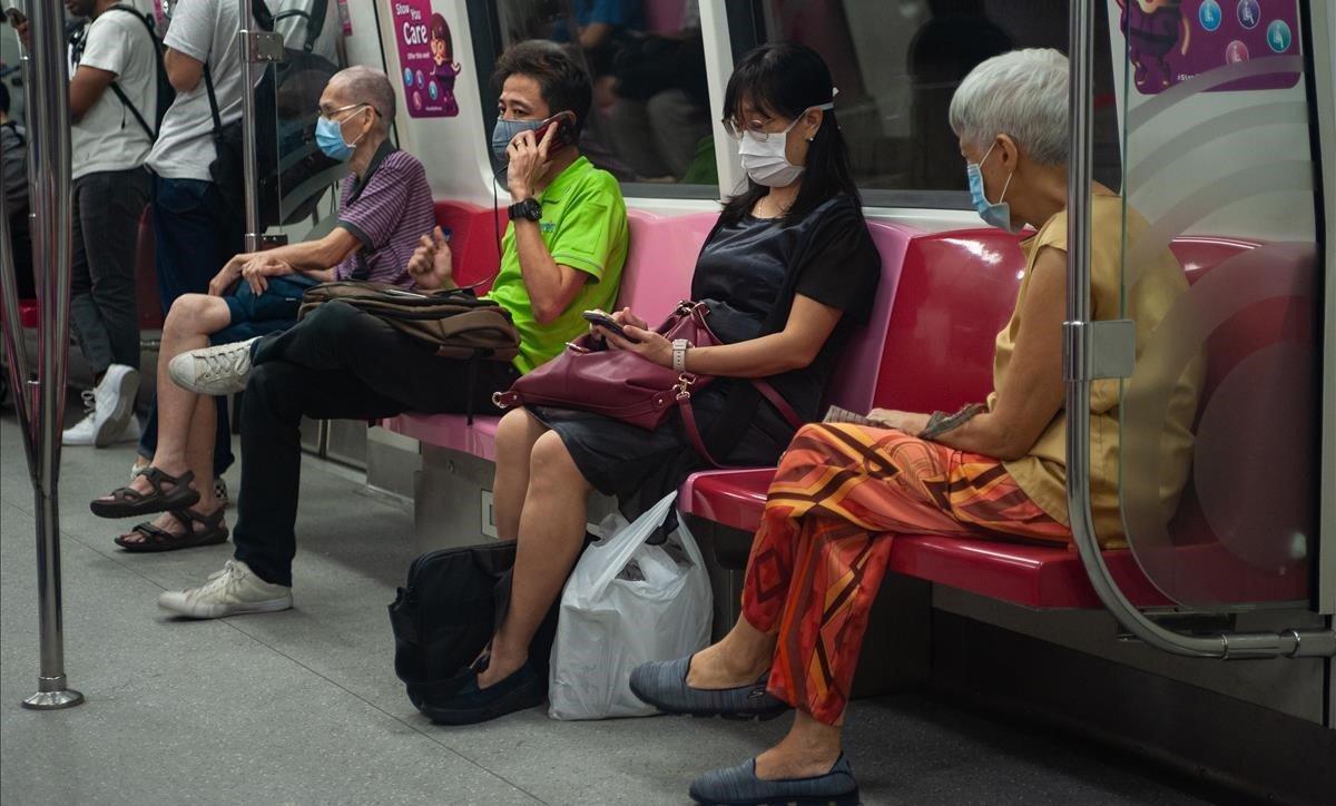 Pasajeros del metro de Singapur viajan protegidos con máscaras y respetando la distancia de seguridad.
