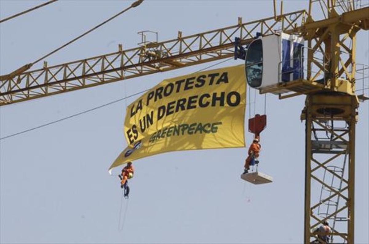 Activistas de Greenpeace despliegan una pancarta contra la ’ley mordaza’ desde una grúa, en el Congreso.