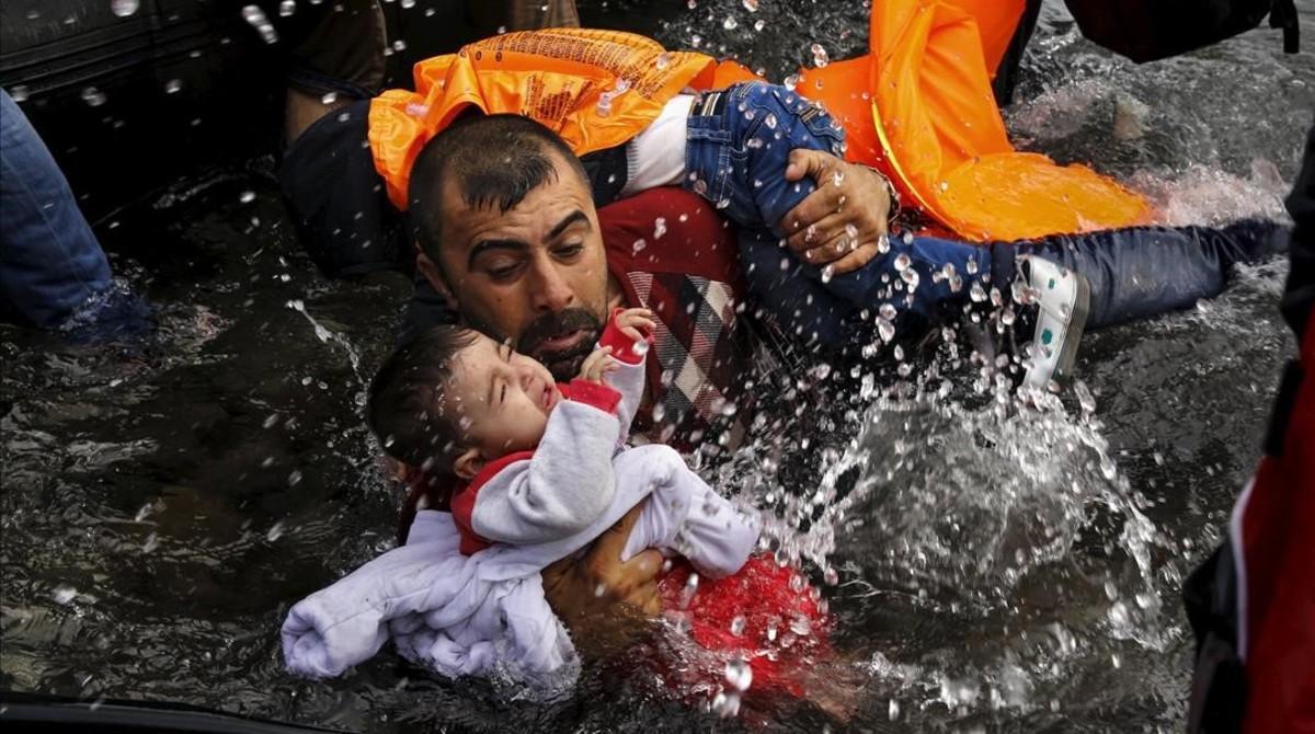 Un refugiado intenta mantener fuera del agua a su hijo para que no se ahogue frente a las costas de Lesbos. Un refugiado intenta mantener fuera del agua a su hijo para que no se ahogue frente a las costas de Lesbos.