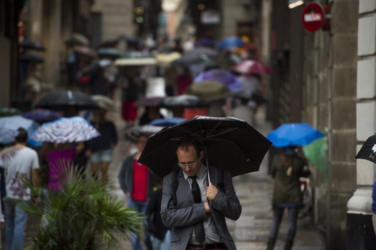 Vianants es protegeixen de la pluja amb paraigües pels carrers del barri gòtic el setembre passat