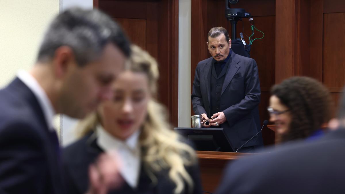 Amber Heard, desenfocada en primer plano, y Johnny Depp, durante el juicio.