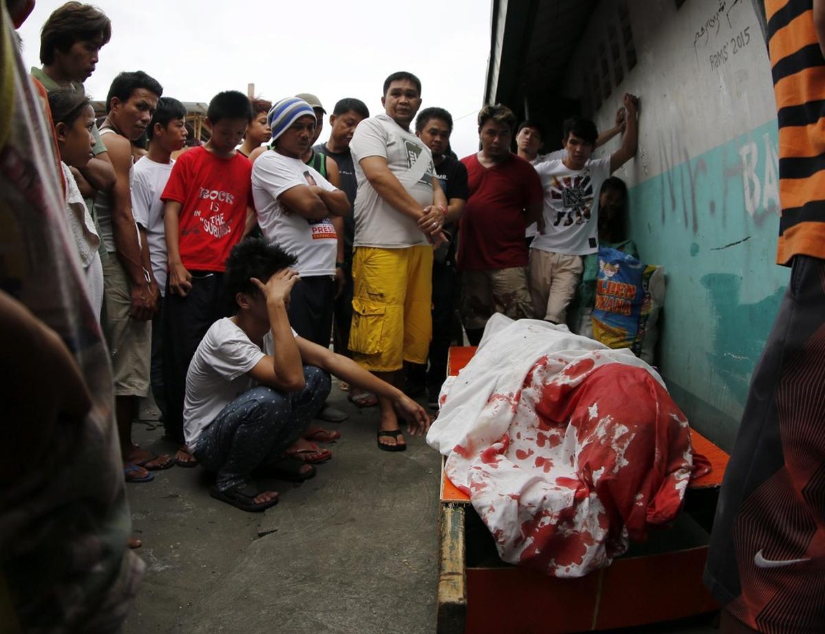 Un grupo de familiares permanece junto al cuerpo de un supuesto drogadicto asesinado durante una operación policial contra las drogas ilegales al interior de una mezquita en Manila.