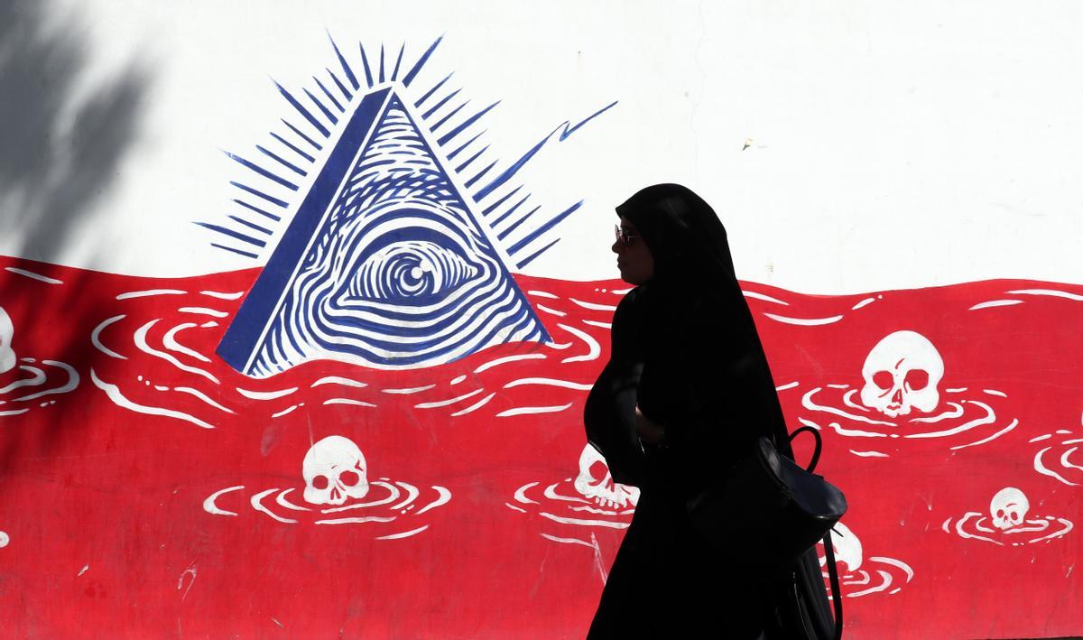 Una mujer iraní pasa frente a un mural.