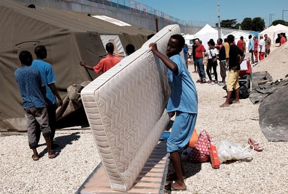 Un eritreo carga con un colchón en un campo de refugiados en Roma. Un eritreo carga con un colchón en un campo de refugiados en Roma.