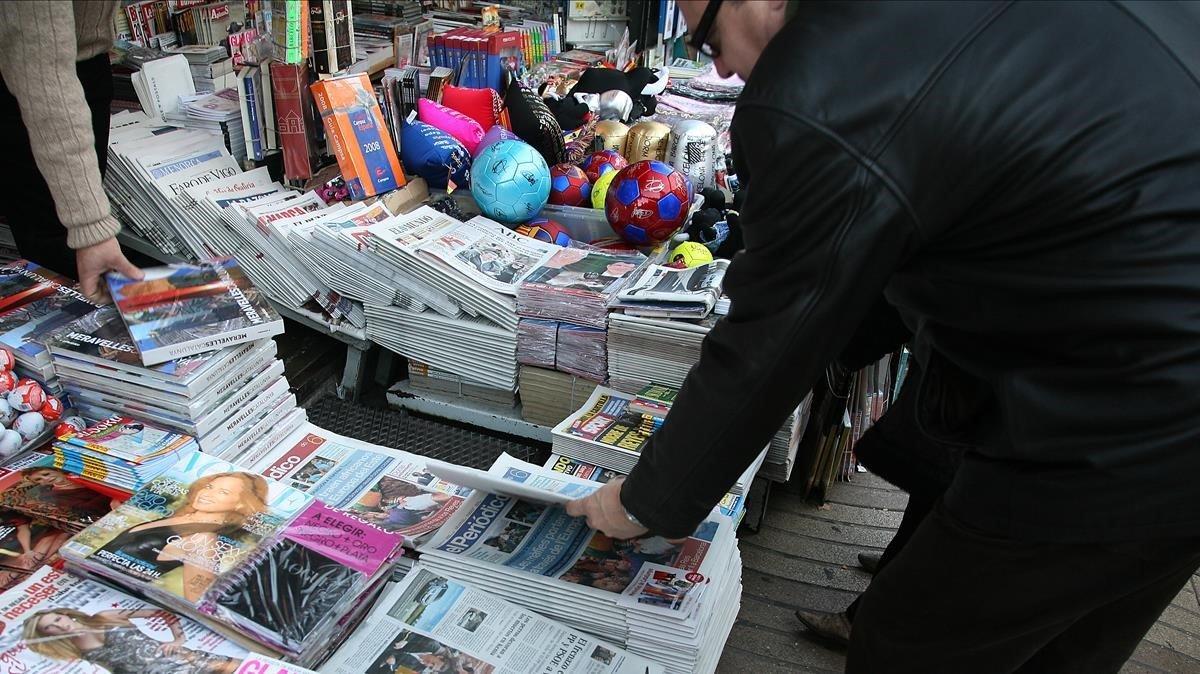 Un hombre compra un periódico en un quiosco de Barcelona.