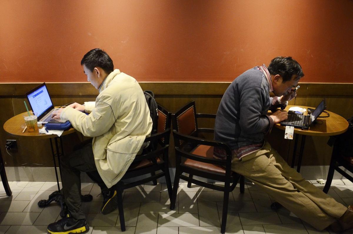 Dos hombres usan sus portátiles en un café de Shanghái.