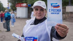 Una voluntaria reparte panfletos con el mensaje Siempre con Rusia durante la campaña para el referéndum para unirse a la Federación Rusa, en Luhansk, Ucrania.