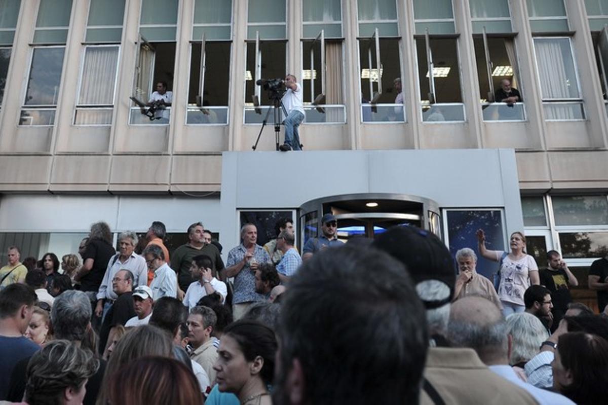 Centenares de personas se manifestan a las puertas de la sede de la radiotelevisión pública griega, este martes, en Atenas. Centenares de personas se manifestan a las puertas de la sede de la radiotelevisión pública griega, este martes, en Atenas.