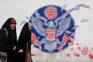 Chicas con velo junto a un mural antiestadounidense en Teherán.