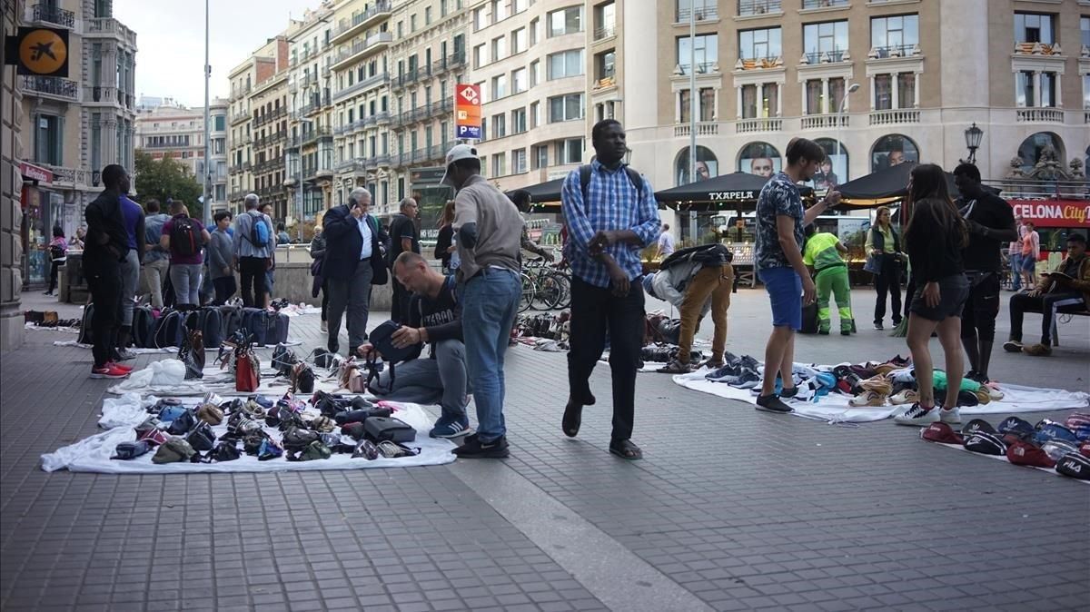 Un grupo de manteros venden sus productos a los turistas este domingo en Plaza Catalunya Un grupo de manteros venden sus productos a los turistas este domingo en Plaza Catalunya