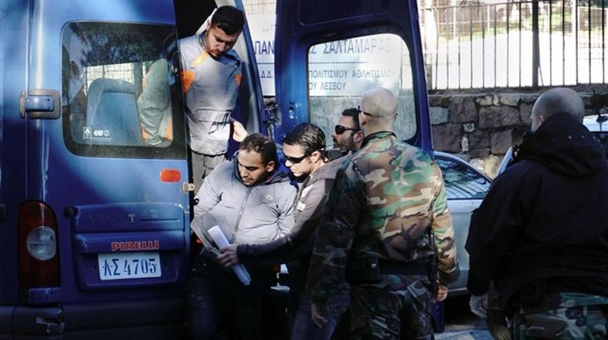 Dos de los detenidos salen de una furgoneta de la policía griega.