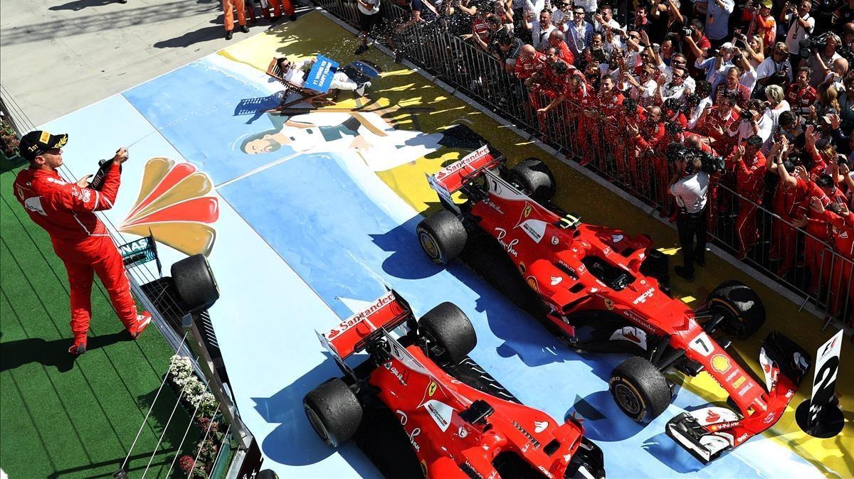 Sebastian Vettel celebra la victoria en el podio de Hungaroring mientras Alonso posa sobre un mural con la icónica imagen en una tumbona de Brasil-2015.