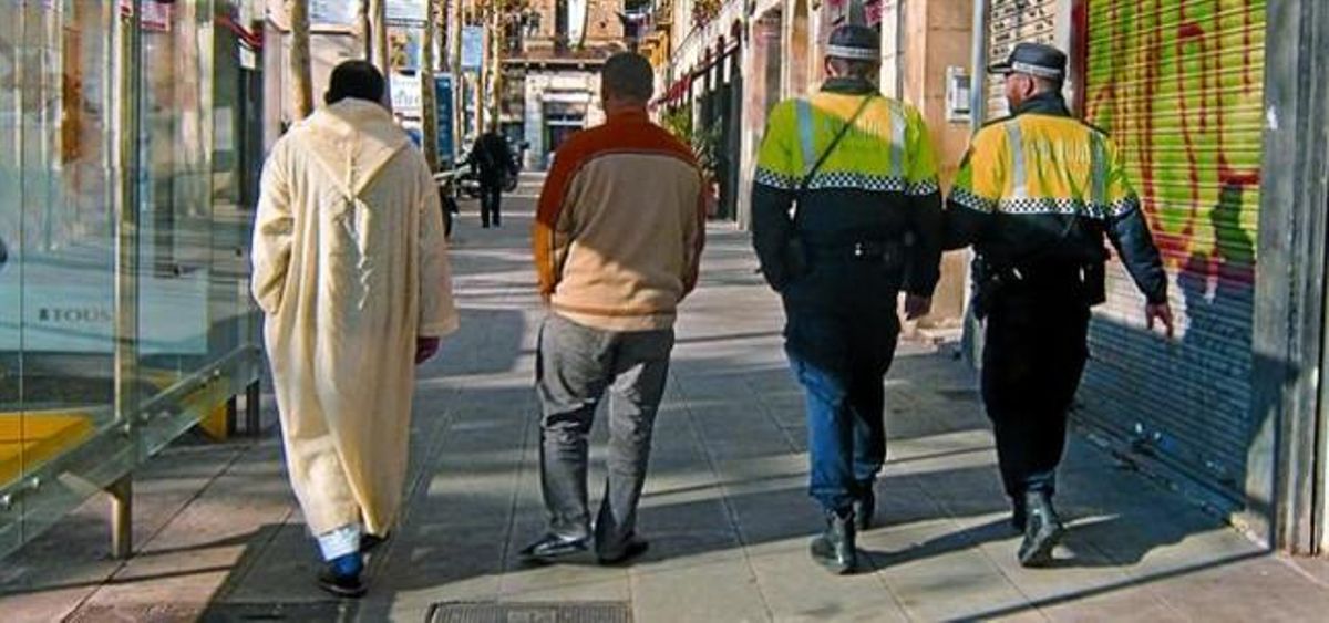 Inmigrantes y agentes de la Guardia Urbana pasean por la rambla del Raval, el pasado viernes. Inmigrantes y agentes de la Guardia Urbana pasean por la rambla del Raval, el pasado viernes.