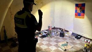 Un agente de la Policía Local de Mataró inspecciona las pertinencias de un okupa en el inmueble donde vive, al lado del centro de la ciudad