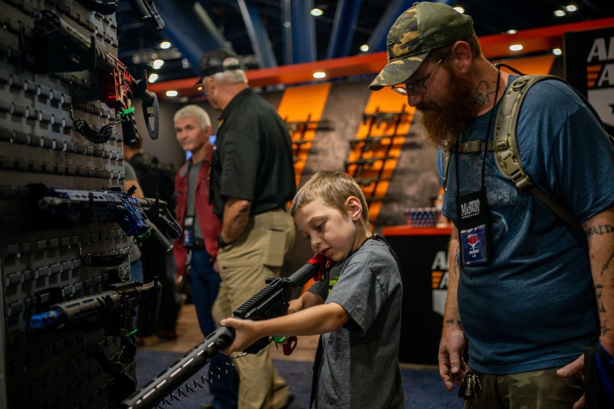 Un padre observa cómo su hijo sostiene un rifle AR-15 durante la convención de la Asociación Nacional del Rifle en Houston, este sábado.