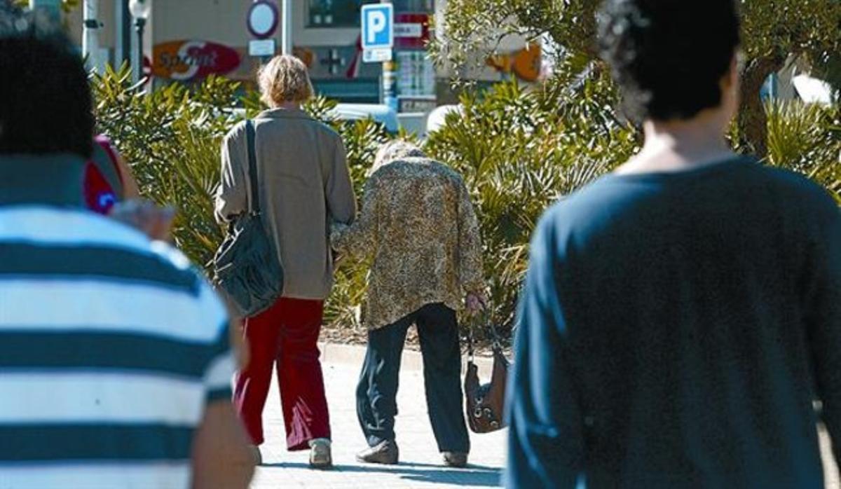 Una mujer de mediana edad pasea con una anciana en Barcelona. Una mujer de mediana edad pasea con una anciana en Barcelona.