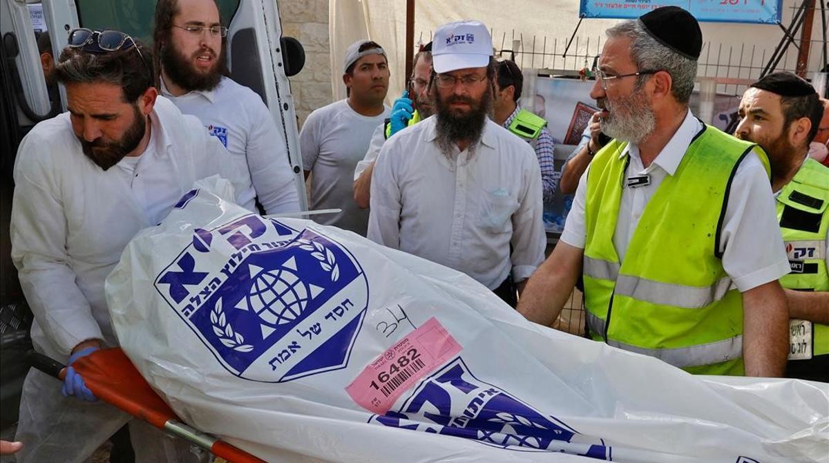Miembros de los equipos de rescate trasladan el cuerpo de un fallecido tras la estampida que se ha producido durante un encuentro religioso en Meron (Israel).