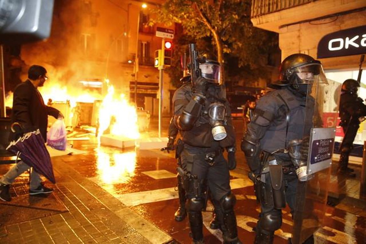 Agentes antidisturbios bloquean una calle mientras detrás arden varios contenedores, esta noche, en Sants. Agentes antidisturbios bloquean una calle mientras detrás arden varios contenedores, esta noche, en Sants.