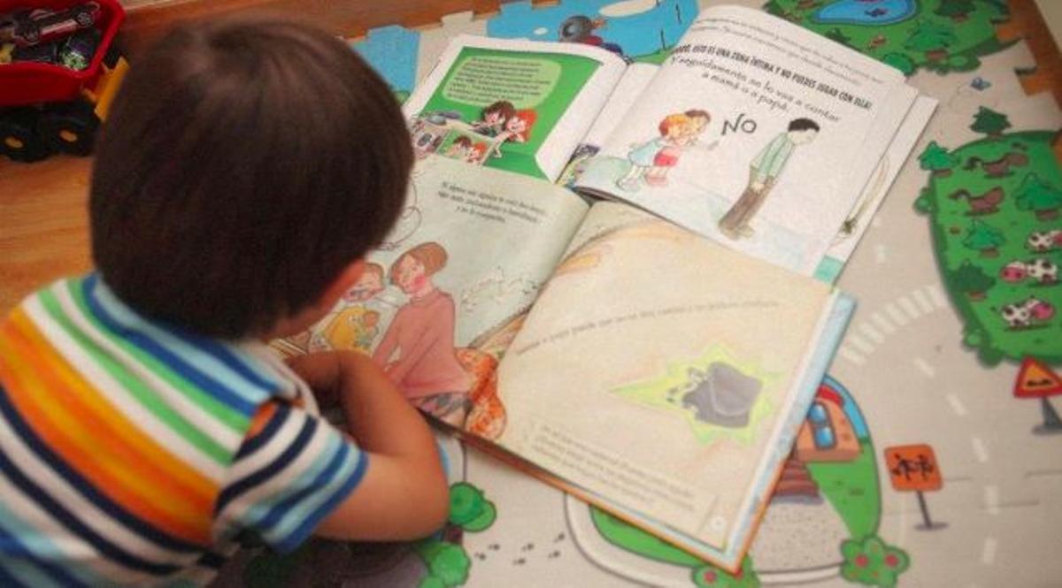 Un niño de tres años mira las viñetas de unos cuentos infantiles para prevenir el abuso sexual, en su casa de Madrid.