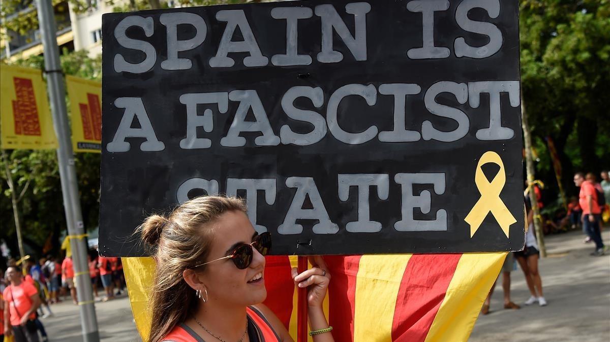 Una joven con un pancarta en la que se lee: España es un estado fascista