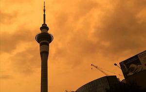 La silueta de la Sky Tower en Auckland (Nueva Zelanda) recortada contra un cielo naranja.