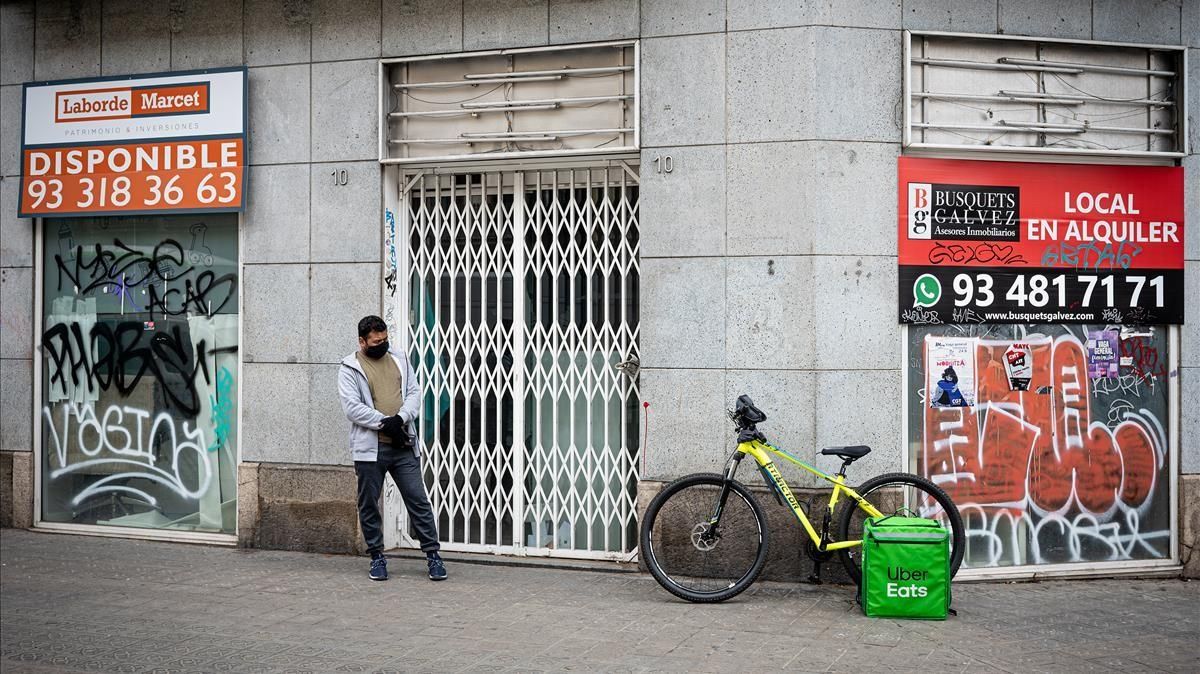 Un repartidor de comida delante de un establecimiento cerrado, en Barcelona. Un repartidor de comida delante de un establecimiento cerrado, en Barcelona.