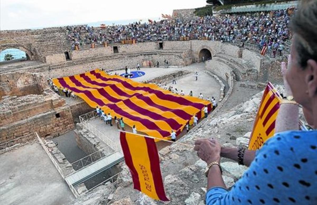 La gran ’senyera’ desplegada por Societat Civil Catalana en Tarragona, con una participante que enarbola una bandera española.