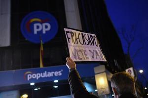 Un hombre sostiene un cartel contra el líder de los populares, Pablo Casado, y en defensa de la presidenta de la Comunidad de Madrid, Isabel Díaz Ayuso, frente a la sede del PP en la madrileña calle de Génova, este 18 de febrero de 2022.