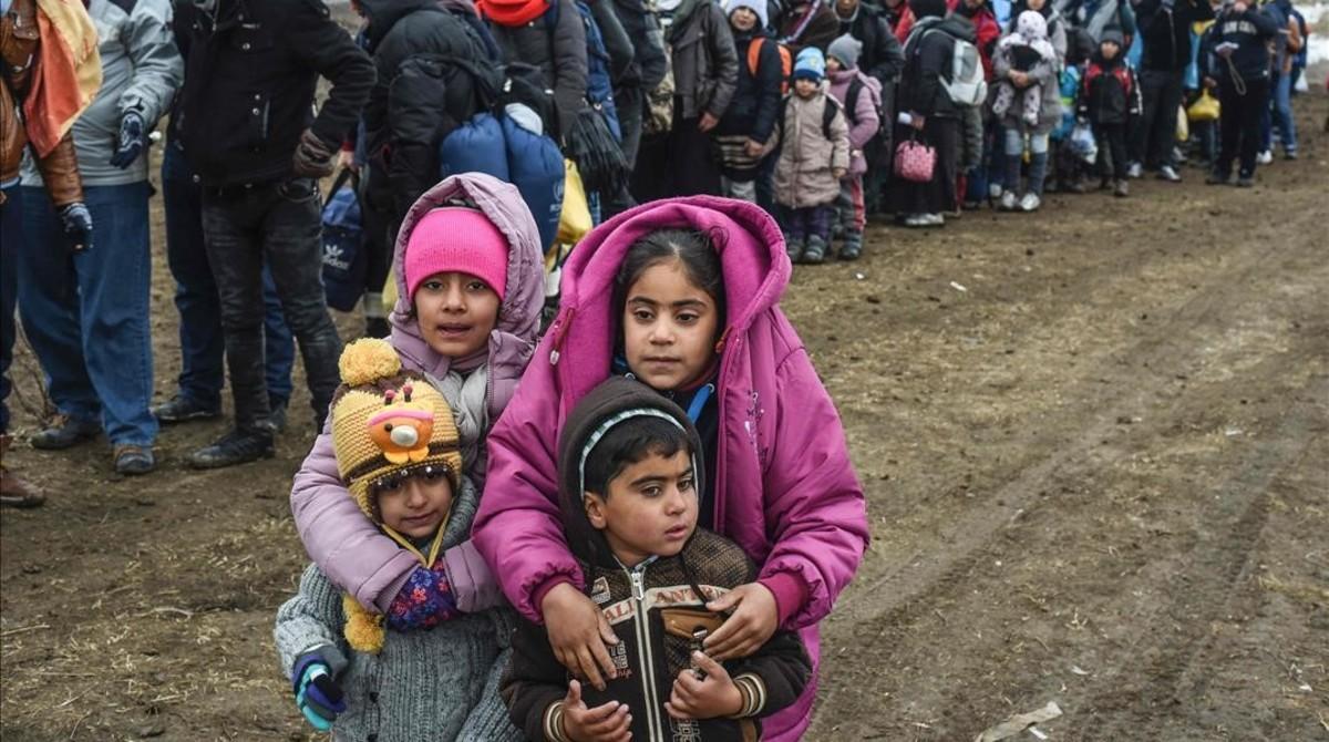 Unos niños sirios esperan junto a otros refugiados para cruzar la frontera entre Macedonia y Serbia.