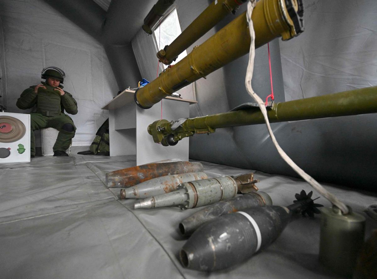 Un desminador de la Guardia Nacional de Ucrania observa armamento abandonado por las tropas rusos en la zona de Chernóbil.