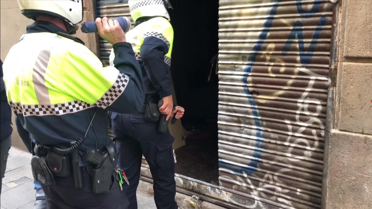 Dos agentes de la Guardia Urbana entran este martes pistola en mano en un narcopiso que no pudo ser clausurado durante la operación Bacar. Dos agentes de la Guardia Urbana entran este martes pistola en mano en un narcopiso que no pudo ser clausurado durante la operación Bacar.