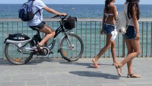 Un turista con una bicicleta eléctrica, en el paseo Marítimo de la Barceloneta.