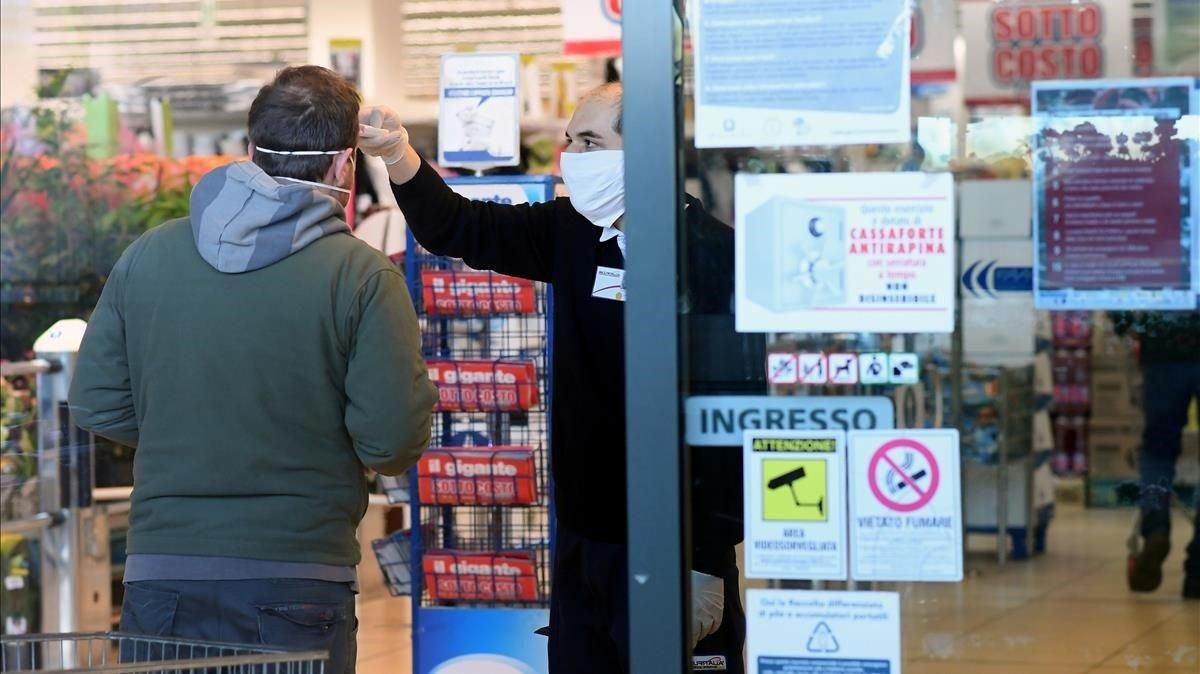 Un empleado de un supermercado toma la temperatura de un cliente a la entrada del establecimiento, el lunes en Milán. Un empleado de un supermercado toma la temperatura de un cliente a la entrada del establecimiento, el lunes en Milán.