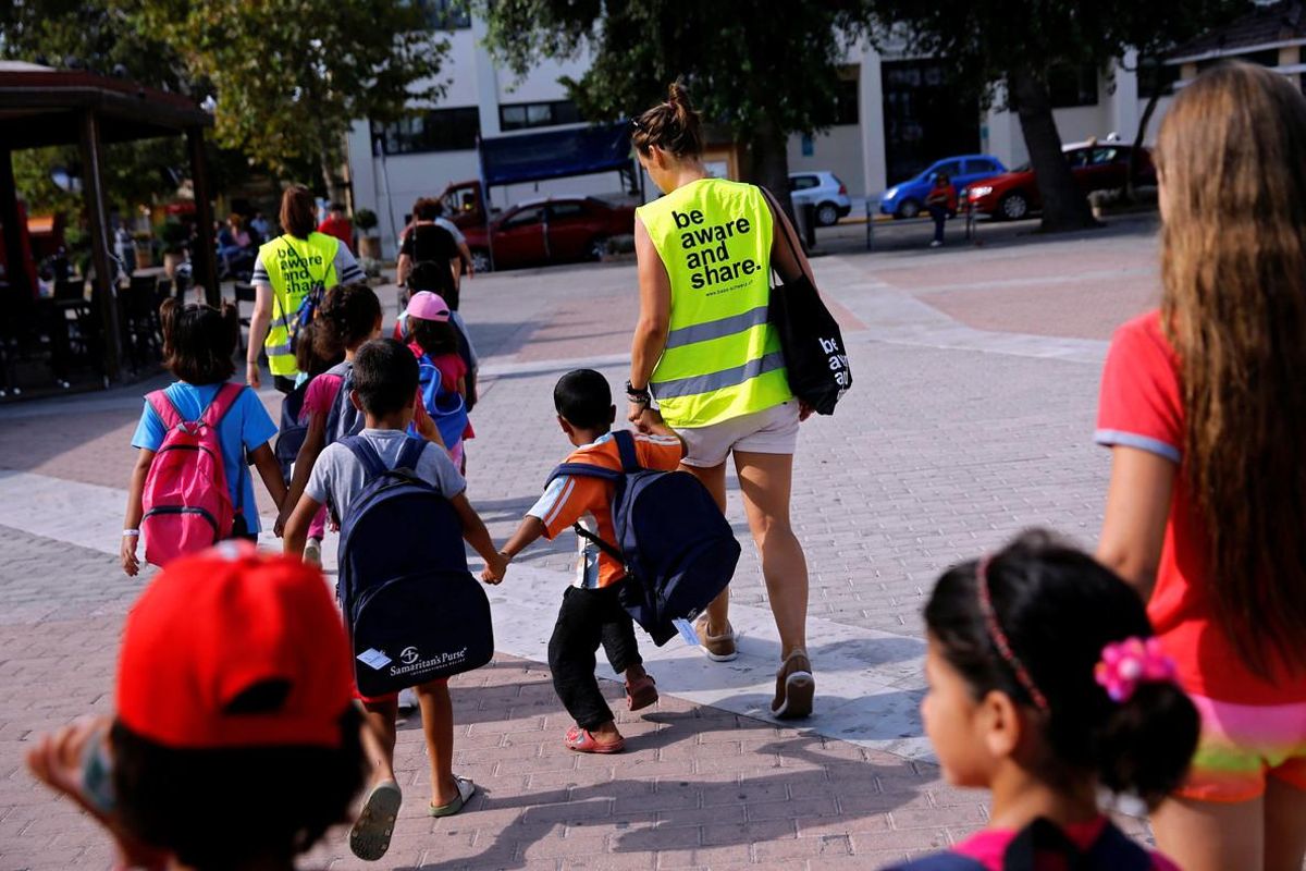 Unos voluntarios acompañan a la escuela a niños refugiados en la isla griega de Chios. Unos voluntarios acompañan a la escuela a niños refugiados en la isla griega de Chios.