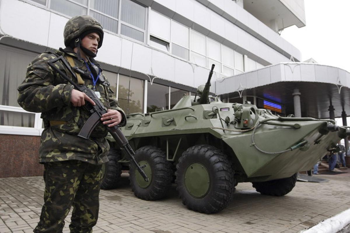 Un soldado ucraniano hace guardia junto a un vehículo blindado en el aeropuerto de Kiev.