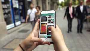 Una usuaria de Wallapop consulta la aplicación en su teléfono desde una calle de Barcelona.