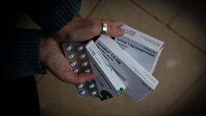 Una persona sujeta varias cajas de medicamentos, una de ellas de Orfidal (Lorazepam)