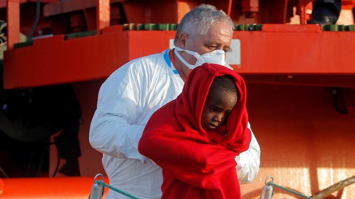 Un miembro de Salvamento Marítimo desembarca en el puerto de Málaga a uno de los menores rescatados en una patera en el Mar de Alborán este martes. Un miembro de Salvamento Marítimo desembarca en el puerto de Málaga a uno de los menores rescatados en una patera en el Mar de Alborán este martes.