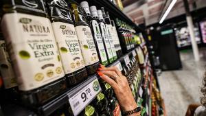 Una mujer elige entre varias botellas de aceite en un supermercado de Barcelona
