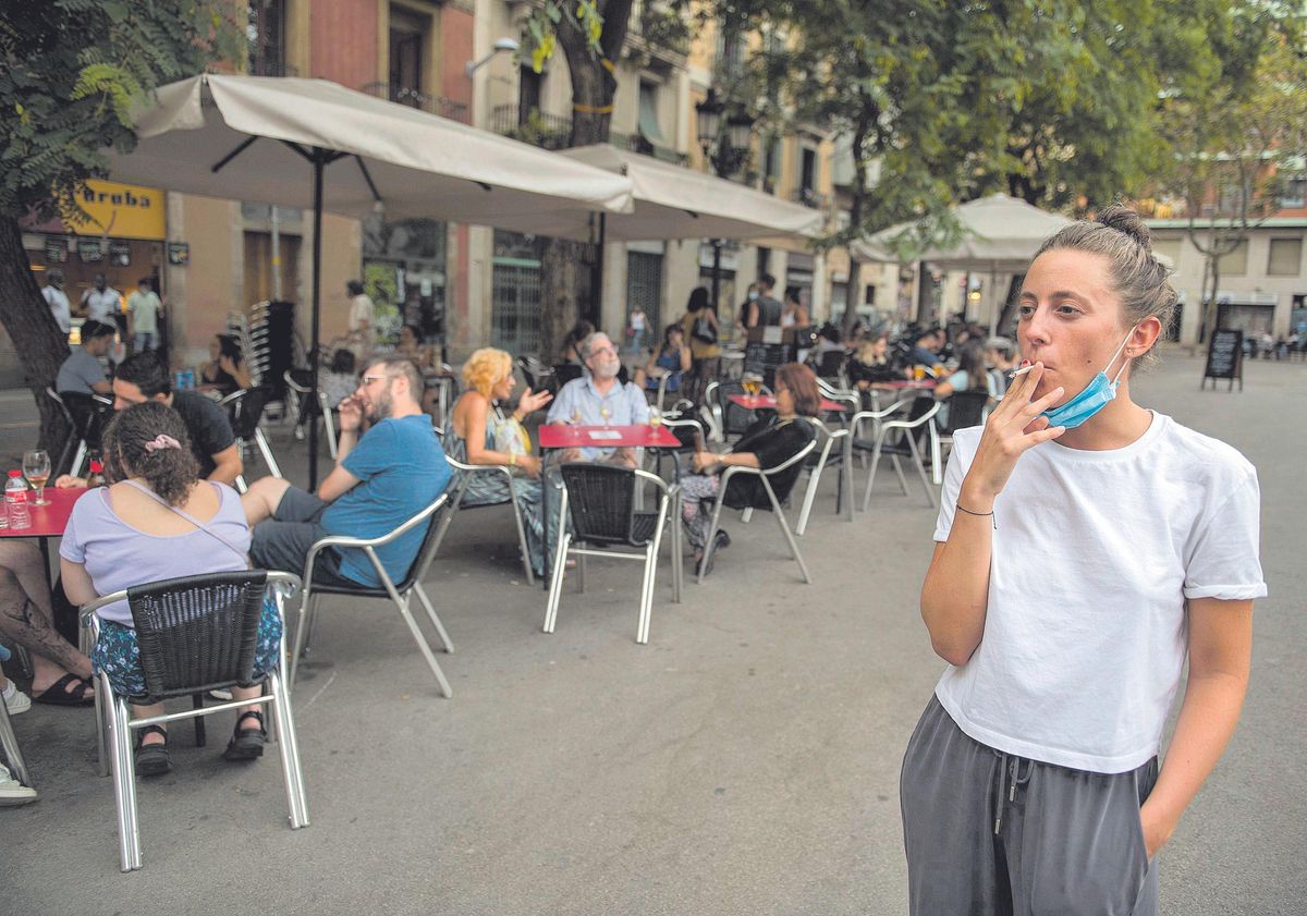 Una joven fuma al lado de una serie de terrazas, en Barcelona. Una joven fuma al lado de una serie de terrazas, en Barcelona.