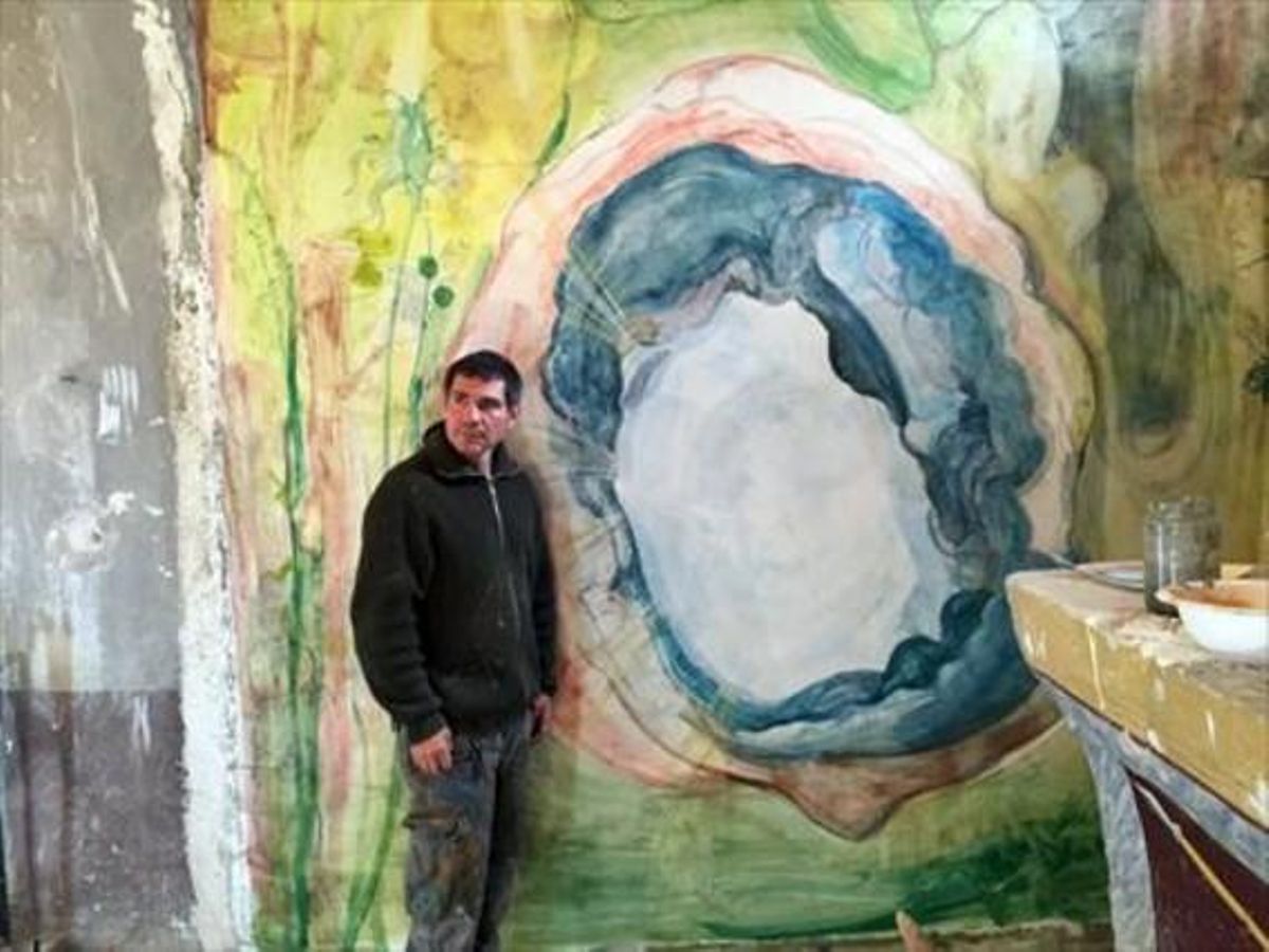 El artista Santi Moix, junto a uno de los frescos y coloristas murales que ha pintado en la iglesia Sant Víctor de Saurí del siglo XII. El artista Santi Moix, junto a uno de los frescos y coloristas murales que ha pintado en la iglesia Sant Víctor de Saurí del siglo XII.